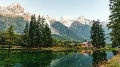 a lake with a house and mountains in the background at Villa Loppe - Chamonix Mountain Four-Bedroom Hidden Gem in Chamonix-Mont-Blanc