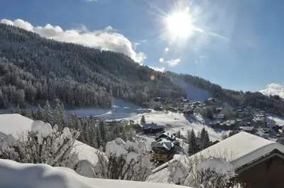 a village in the snow with the sun in the sky at Chalet Haut Standing à proximité du centre (CH228) in Les Carroz d'Araches