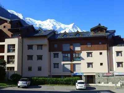 a building with two cars parked in a parking lot with a mountain at Apartment L'Espace Montagne-15 by Interhome in Chamonix-Mont-Blanc