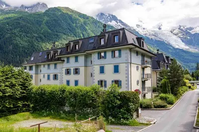 a large white house with mountains in the background at Le Paradis 28 Apartment- Chamonix All Year in Chamonix-Mont-Blanc