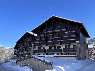 a large building with snow in front of it at Appartement Central 6 Pers, Parking, Ascenseur, Proche Pistes et Commerces - FR-1-572-22 in Les Carroz d'Araches