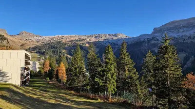 a building on a hill with trees and mountains at Résidence Les Pleiades - Appartement lumineux et confortable · Centre station · Balcon · Parking couvert MAE-7351 in Flaine