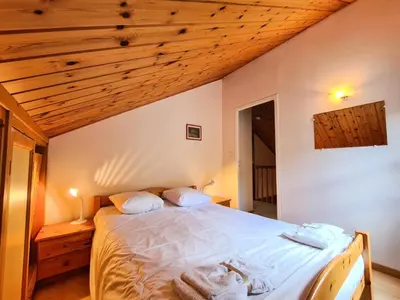 a bedroom with a bed with white sheets and wooden ceilings at Résidence Hameau - Chalet lumineux · Poêle à bois · WIFI gratuit et illimité · Garage MAE-7353 in Flaine
