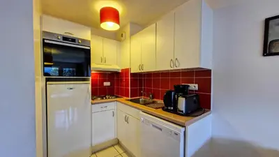 a kitchen with white cabinets and red tile at Résidence Les Pleiades - Appartement spacieux et lumineux · Centre station · Balcon · Parking couvert MAE-7354 in Flaine