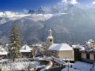 a snowy village with a church and mountains in the background at Apartment Les Capucins by Interhome in Chamonix-Mont-Blanc