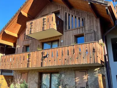 a house with a wooden deck on the side of it at Duplex chaleureux près télécabine, balcon & WIFI - FR-1-624-33 in Samoëns
