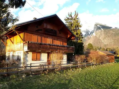 a house in a field with a mountain in the background at Appartement chalet calme, proche centre, animaux acceptés - FR-1-624-45 in Samoëns
