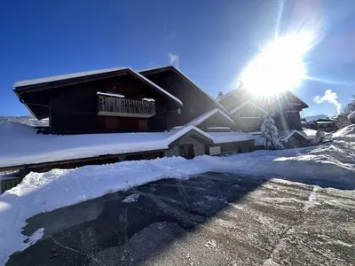 a house covered in snow with the sun behind it at 4 pièces spacieux bien équipé avec Wi-Fi et parking, au pied du ski bus - FR-1-572-241 in Les Carroz d'Araches