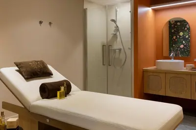 a bathroom with a shower and a bed and a sink at RockyPop Flaine Appartements & Spa in Flaine