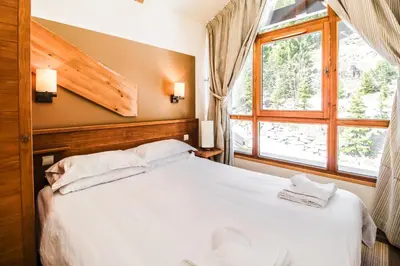 a bedroom with a white bed and a window at Charming 6th-floor 2-bedroom apartment with fireplace in Flaine