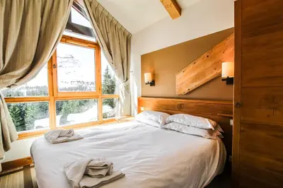 a bedroom with a large bed with a window at Two internally connecting 2-bed apartments with shared private entrance in Flaine