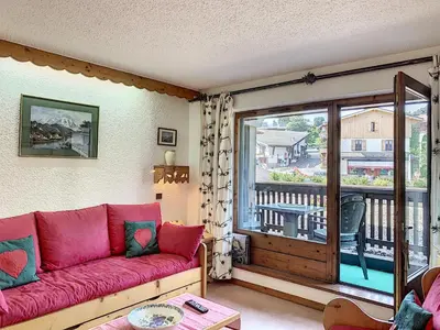a living room with a red couch and a balcony at Joli 2 pièces + studio au centre de Combloux - FR-1-560-74 in Combloux