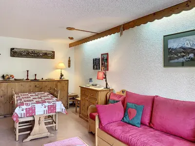 a living room with a pink couch and a table at Joli 2 pièces + studio au centre de Combloux - FR-1-560-74 in Combloux