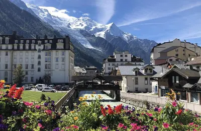 a city with mountains in the background with flowers at Les Alpages - Newly Renovated - 2bed - Equipment Storage - Mont-Blanc Views in Les Houches