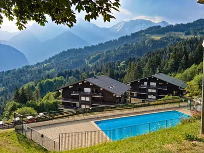 a resort with a swimming pool and mountains in the background at Charmant Studio vue montagne - ski, piscine, tennis, randonnées in Saint-Gervais-les-Bains