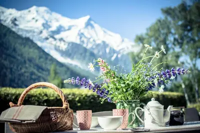 a table with a basket and flowers on a table with a mountain at Paccard Locations Chamonix in Chamonix-Mont-Blanc