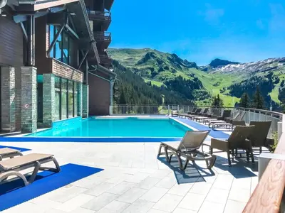 a resort pool with chairs and a view of mountains at Appartement Premium à Flaine, altitude 1740 m, 8 à 10 personnes, au pied des pistes, piscine, jacuzzi, sauna, hammam et salle de sport in Flaine