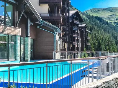 a swimming pool in front of a building with a mountain at Newly redecorated 2-bed ski-in ski-out family apartment in Flaine