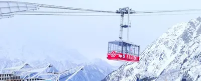 a red cable car flying over a snow covered mountain at Epicea - Chic 2BR in city center, next to Train Station - By Cozee Rentals in Chamonix-Mont-Blanc