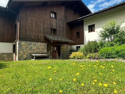 a large wooden building with a field of grass and flowers at Appartement T2 avec grande terrasse et animaux acceptés - FR-1-624-105 in Samoëns
