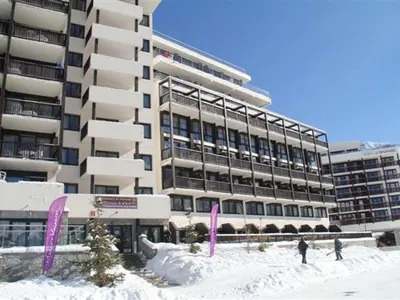 two people standing in the snow in front of a building at Appartement au pied des pistes avec piscine et parking - FR-1-425-189 in Flaine