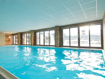 a large swimming pool with blue water in a building at Appartement au pied des pistes avec piscine et parking - FR-1-425-189 in Flaine