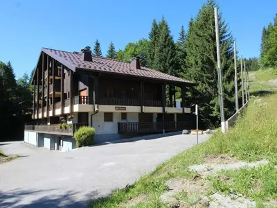a house on a hill with trees in the background at Appartement cosy 5 pers., pied des pistes, balcon est, proche commerces, parking & services - FR-1-572-94 in Arâches-la-Frasse