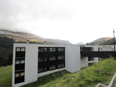 a building in a field with a mountain in the background at Studio rénové à Flaine Forêt - 5 pers, proche des pistes et commerces, balcon sud, casier à skis - FR-1-687-24 in Arâches-la-Frasse