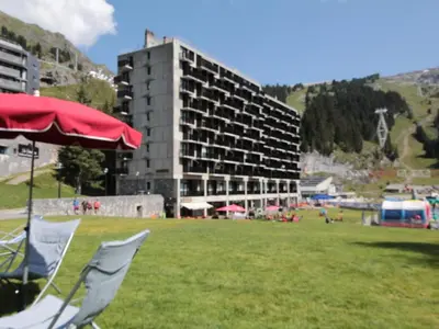 a red umbrella and a chair in a field with a building at Charmant Appartement 2P, 6 Couchages, Pied des Pistes - Résidence Aldebaran, Flaine Forum - FR-1-687-101 in Arâches-la-Frasse