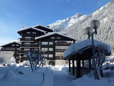a snow covered building in front of a mountain at Studio cosy 3 pers, ski-in/ski-out Chamonix avec wifi et animaux admis - FR-1-343-217 in Chamonix-Mont-Blanc