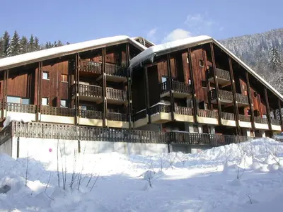 a building with snow on the ground in front of it at Ski aux pieds, 2 pièces rénové, 5 couchages, terrasse, parking, proche commerces et services - FR-1-572-145 in Arâches-la-Frasse