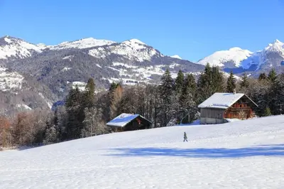 a person skiing down a snow covered slope with buildings at Grand Morillon - 104 - Montagne Belle Vue Studio 4 in Morillon