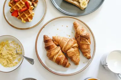 a table topped with plates of croissants and waffles at Apartment Valvisons Les Houches Chamonix - by EMERALD STAY in Les Houches