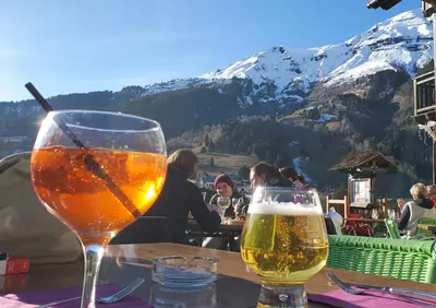 two glasses of beer sitting on a table with a mountain at Studio agréable in Les Contamines-Montjoie