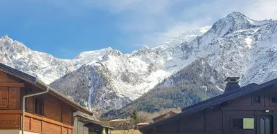 a snow covered mountain range with a house in the foreground at Lilas - Awesome view of the Mont-Blanc Range in Les Houches