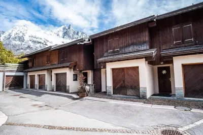 a house with wooden doors and mountains in the background at Chalet Vorgeats 2 - 6 pers - Au pied de la Flégère - Golf - UTMB in Chamonix-Mont-Blanc